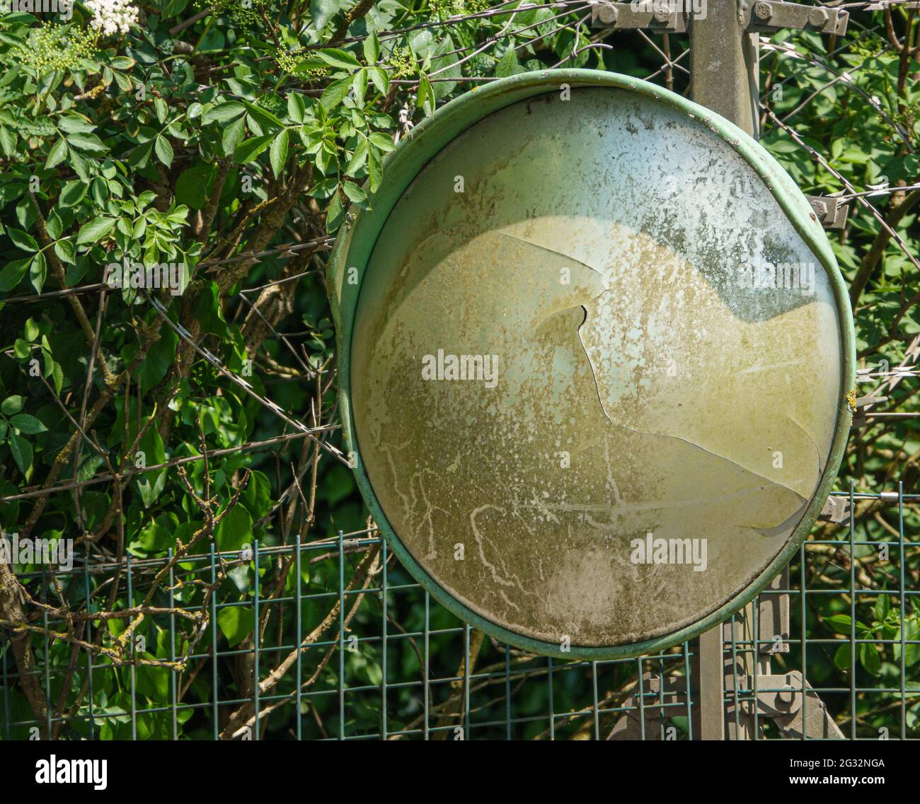 uno specchietto di sicurezza grandangolare vecchio, sbiadito e rotto Foto Stock