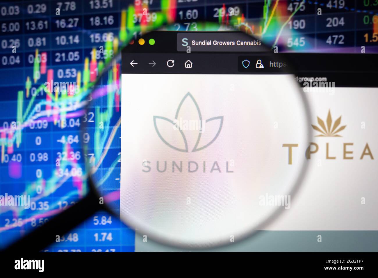 Sundial logo aziendale su un sito web con sviluppi del mercato azionario sfocato in background, visto su uno schermo del computer attraverso una lente di ingrandimento Foto Stock