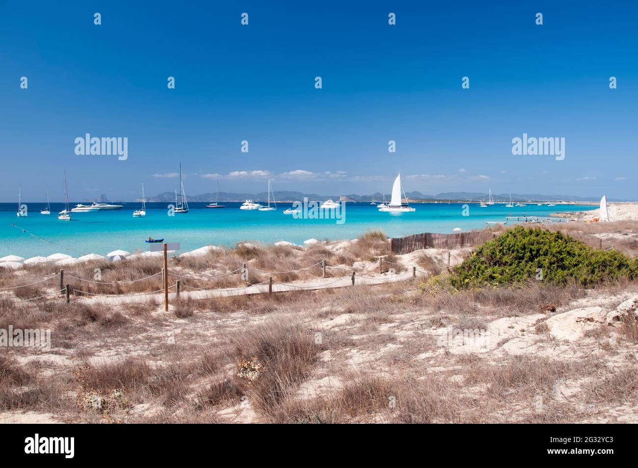 Barche di lusso ancorate vicino alla spiaggia di Ses Illetas. Spiaggia selvaggia sull'isola di Formentera, Spagna Foto Stock