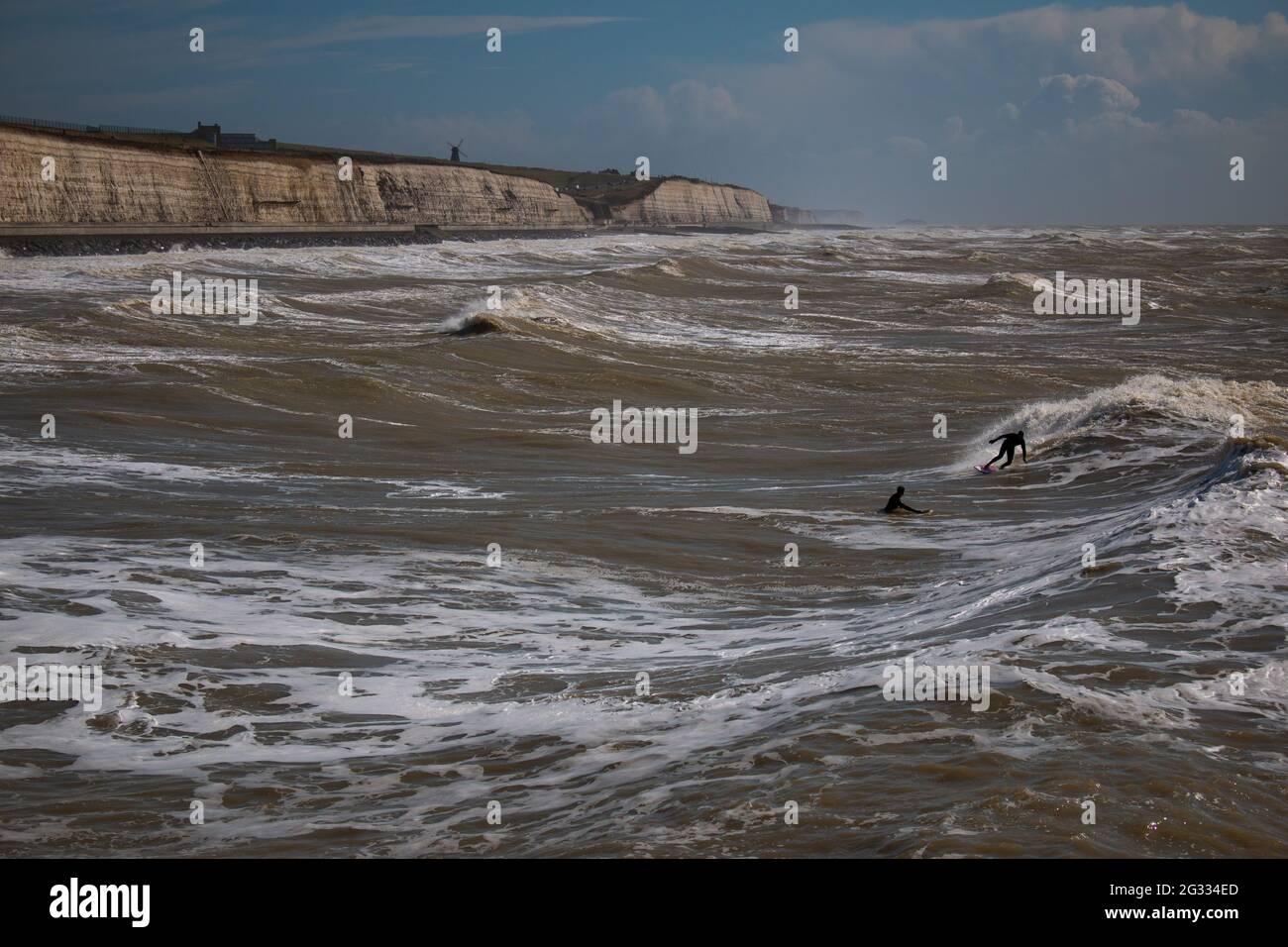 Piccole figure di surfisti vicino alla passeggiata sotto la scogliera di Brighton, Regno Unito Foto Stock