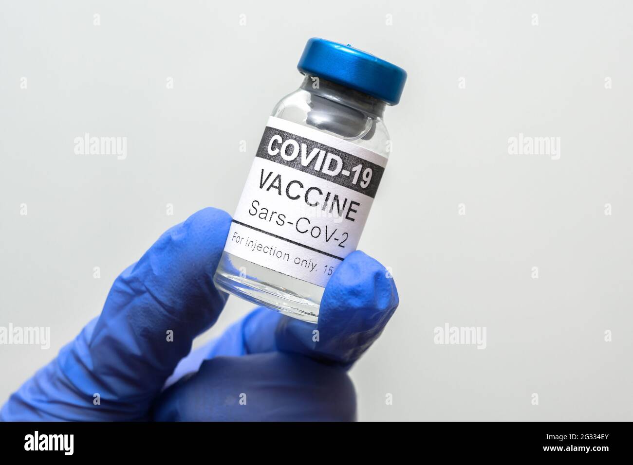 Flaconcino vaccino COVID-19 su fondo bianco, flacone vaccino coronavirus in un primo piano con guanti medici. Concetto di medicina, vaccinazione, immunizzazione, Foto Stock