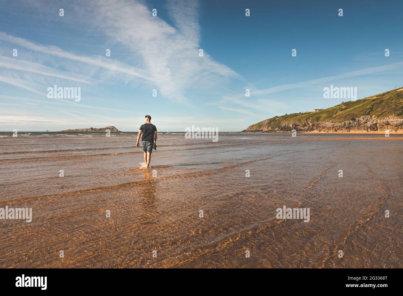 Giovane caucasico che cammina in spiaggia Foto Stock