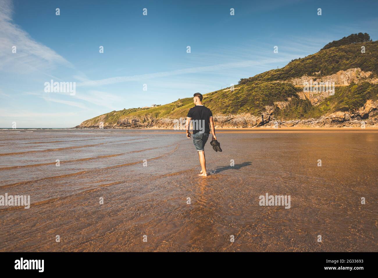 Giovane caucasico che cammina in spiaggia Foto Stock