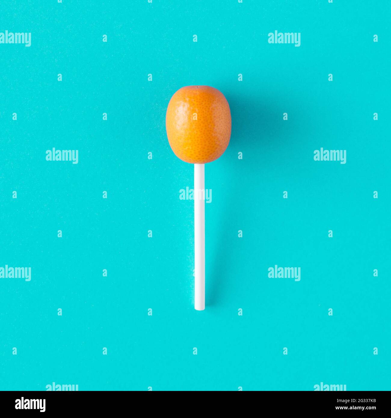 Kumquat frutta arance piccole su un bastone lollipop su uno sfondo turchese blu. Concetto di cibo estivo agli agrumi. Stile fotografico minimo. Foto Stock