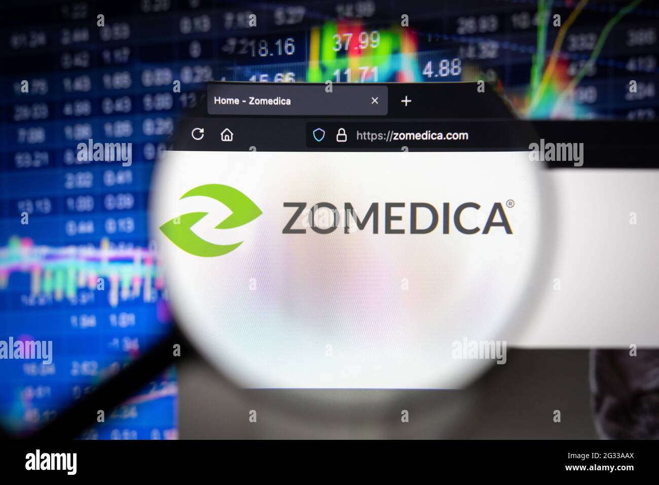 Logo della società Zomedica su un sito web con sviluppi sfocati del mercato azionario in background, visto su uno schermo del computer attraverso una lente di ingrandimento Foto Stock