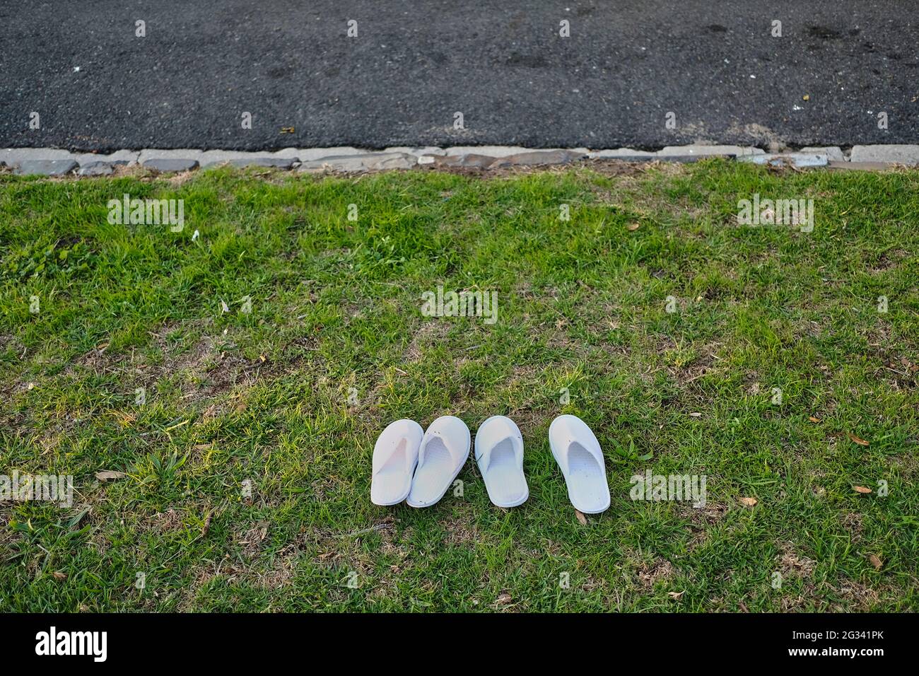 Scarpe da scivola bianche all'esterno su erba verde accanto alla strada del catrame. Foto Stock