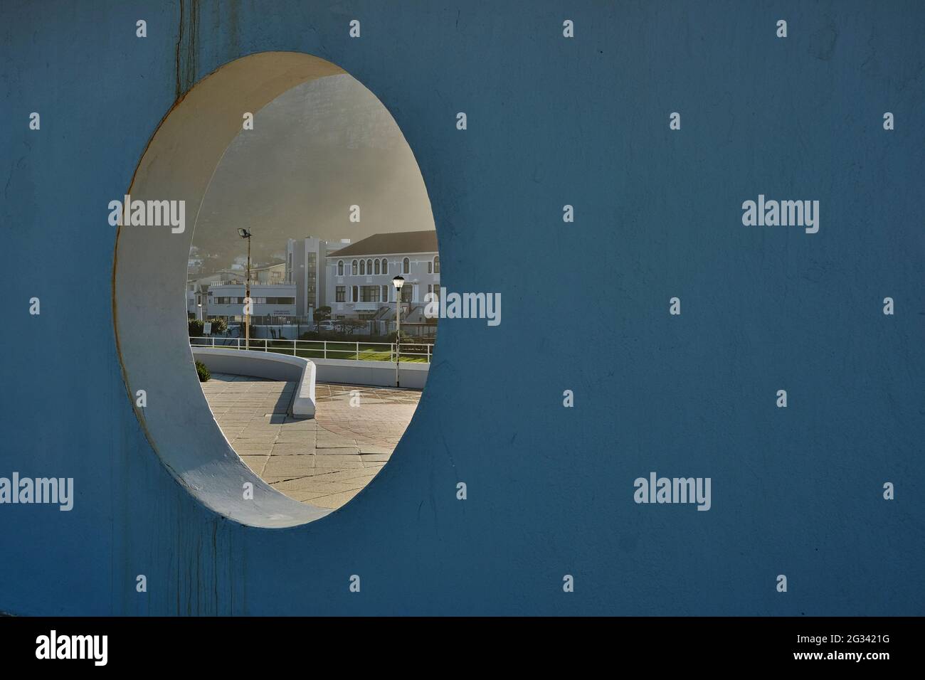 Vista parziale della città costiera di Muizenberg attraverso un buco in un muro. Muizenberg Beach, città del Capo, Sudafrica, giugno 2021 Foto Stock