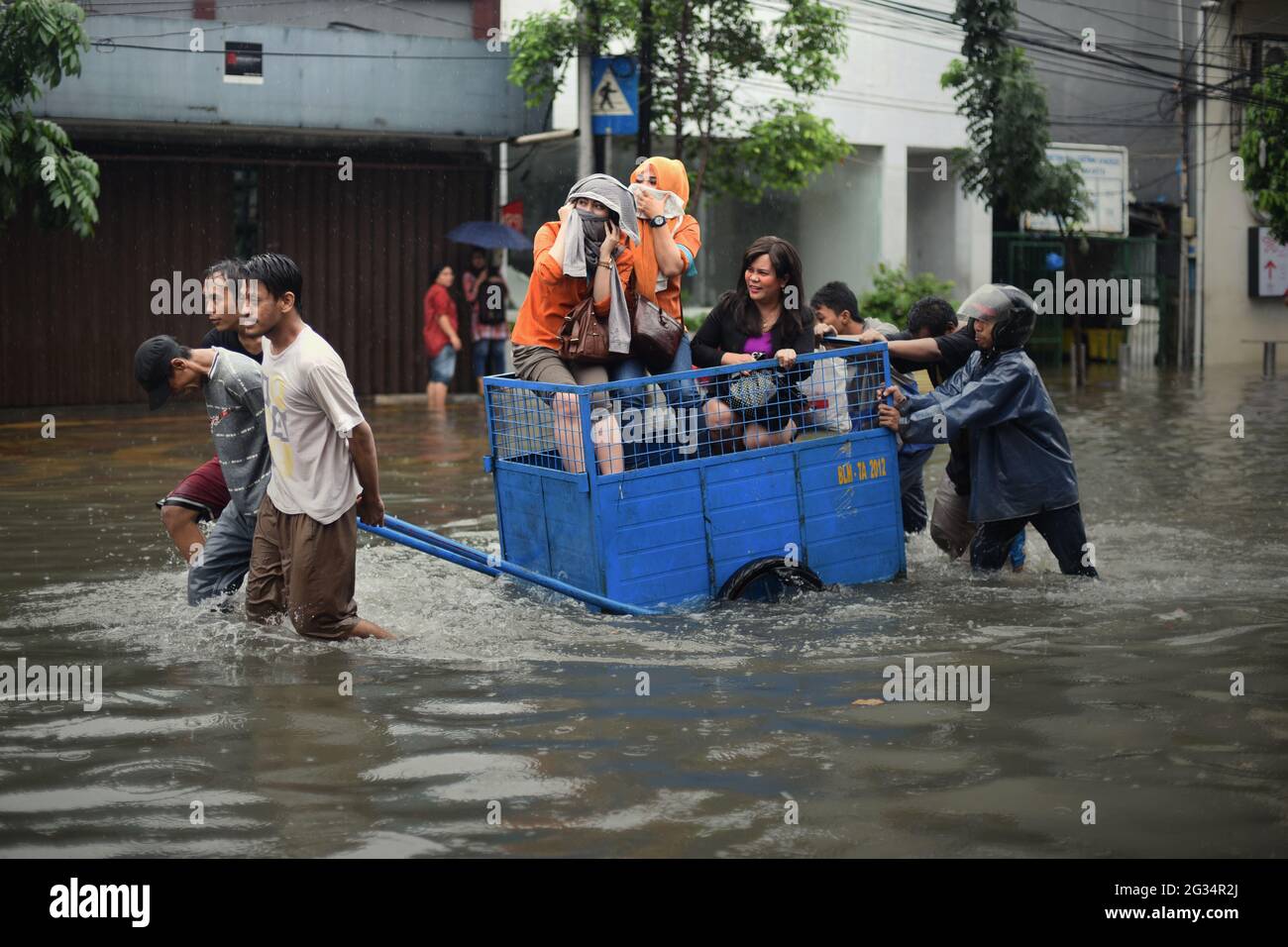 Jakarta, Indonesia. 9th febbraio 2015. Uomini che aiutano le donne a viaggiare attraverso una strada allagata da un carro a Giacarta, dopo una pioggia continua ha lasciato l'area del centro della capitale indonesiana inondato. Foto Stock