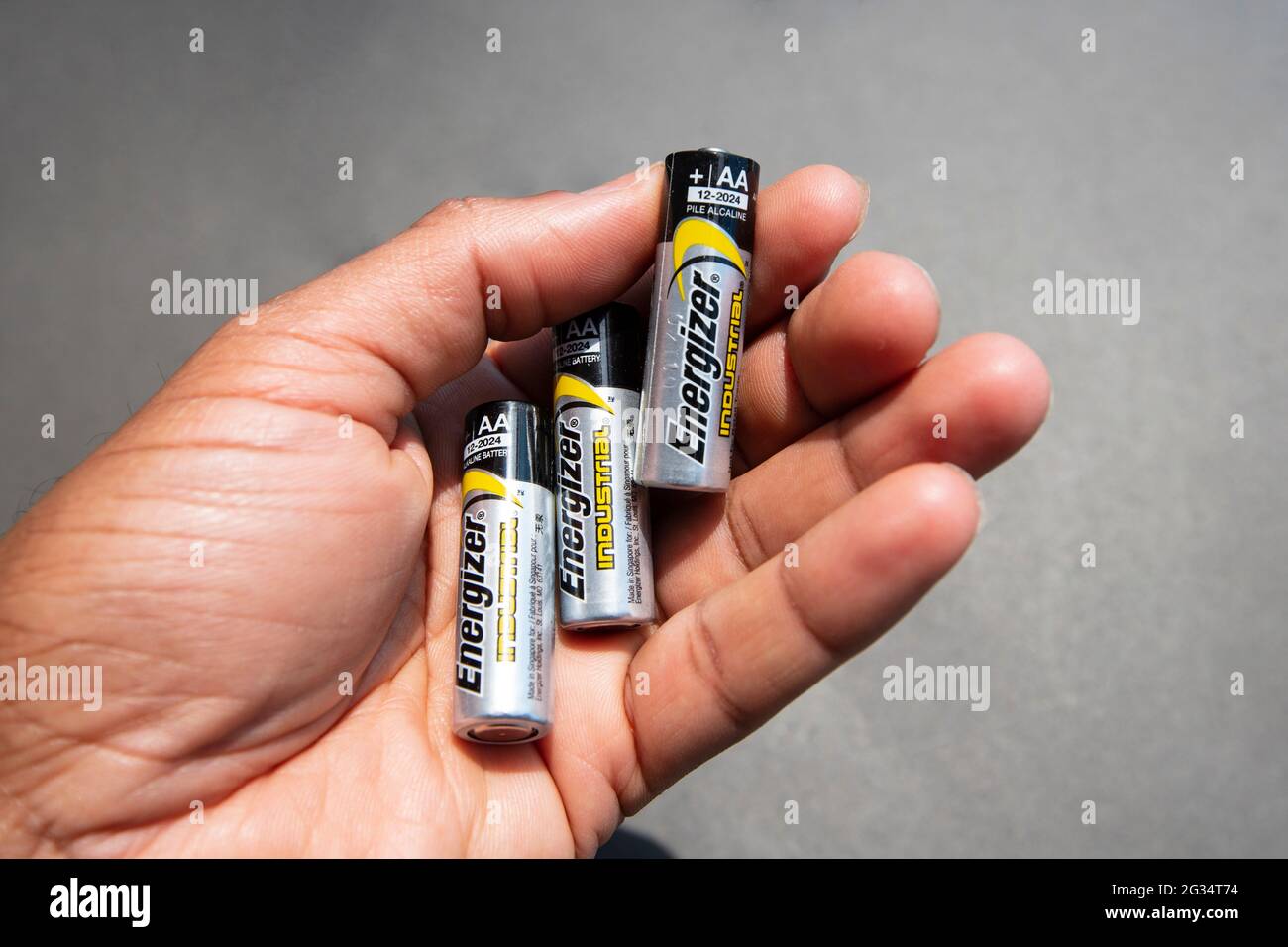 HAMILTON, Ontario, Canada - Giugno 2021: Una mano sta tenendo tre batterie AA Energizer. Foto Stock