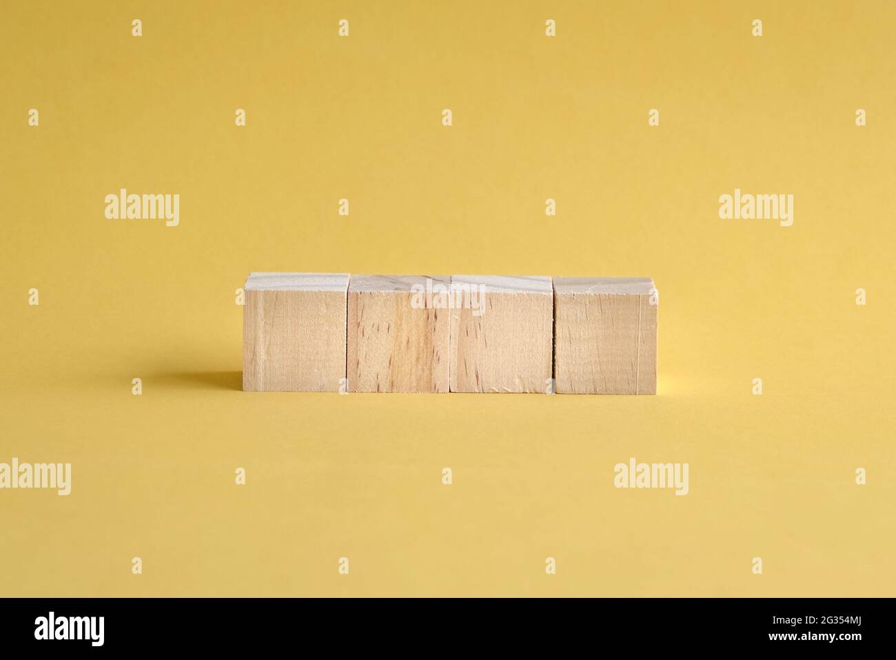 4 lettere vuote e blocchi di legno su sfondo giallo. Foto Stock