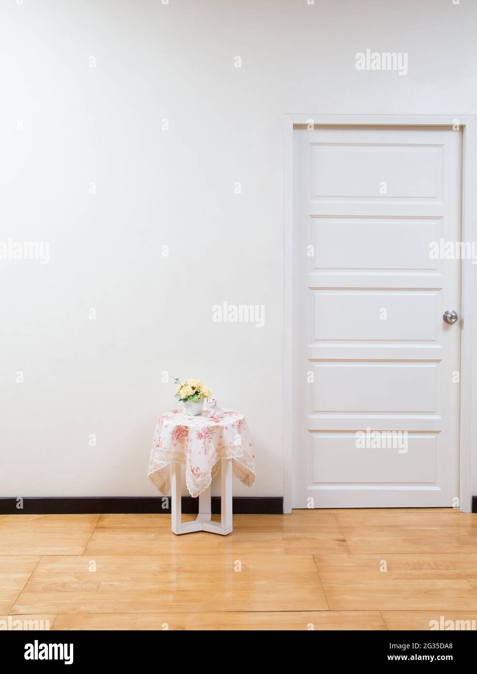 Interno della camera con tavolo, porta bianca e pavimento in legno. Interno di sfondo Foto Stock