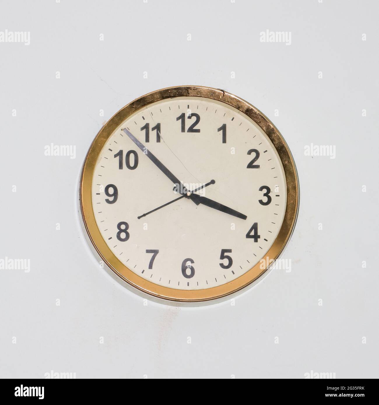 orologio rotondo grande con un design vecchio e semplice e una cornice in oro appesa in una parete bianca che mostra tempo preciso Foto Stock