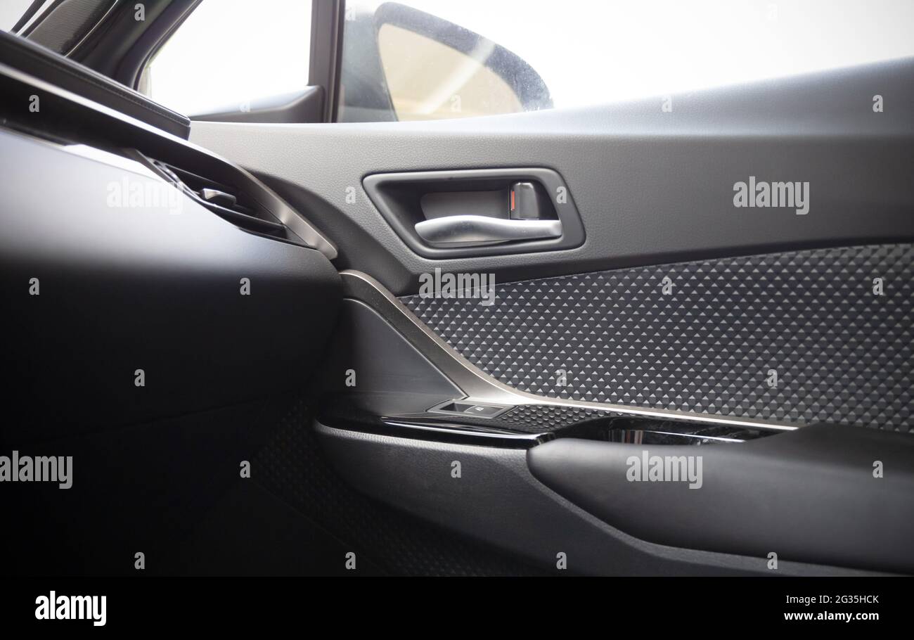 L'interno della vettura con vista sulla portiera lato passeggero con pulsanti, bracciolo e pelle grigia Foto Stock