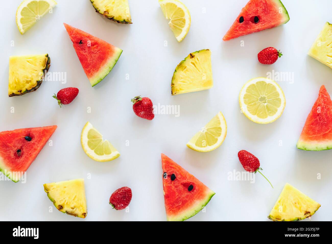 Cocomero, ananas, limone e fragole su sfondo bianco. Texture. Foto Stock
