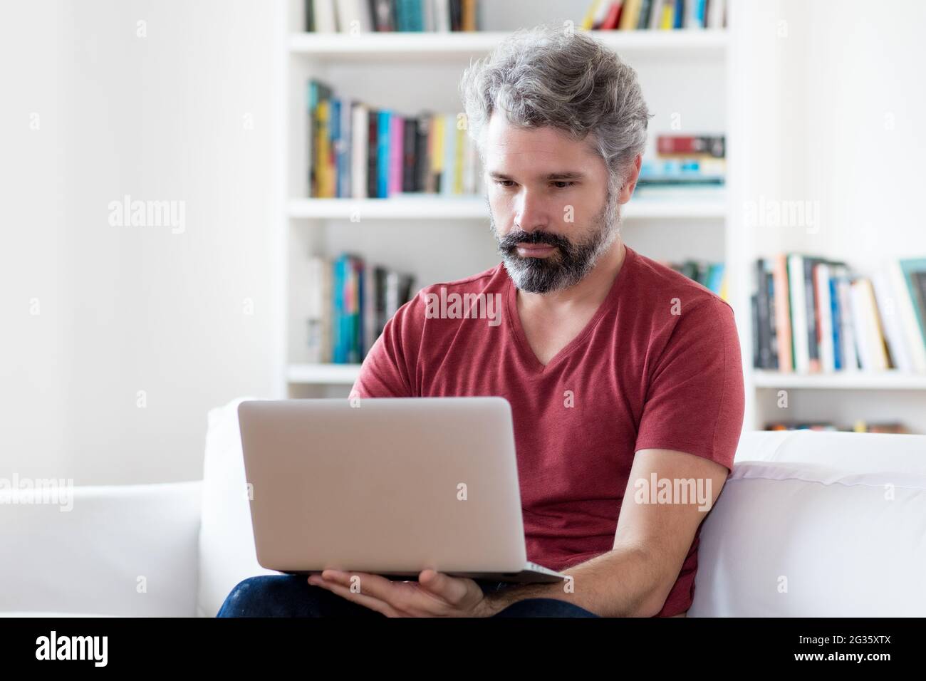 Uomo adulto maturo che lavora al computer all'interno di casa Foto Stock