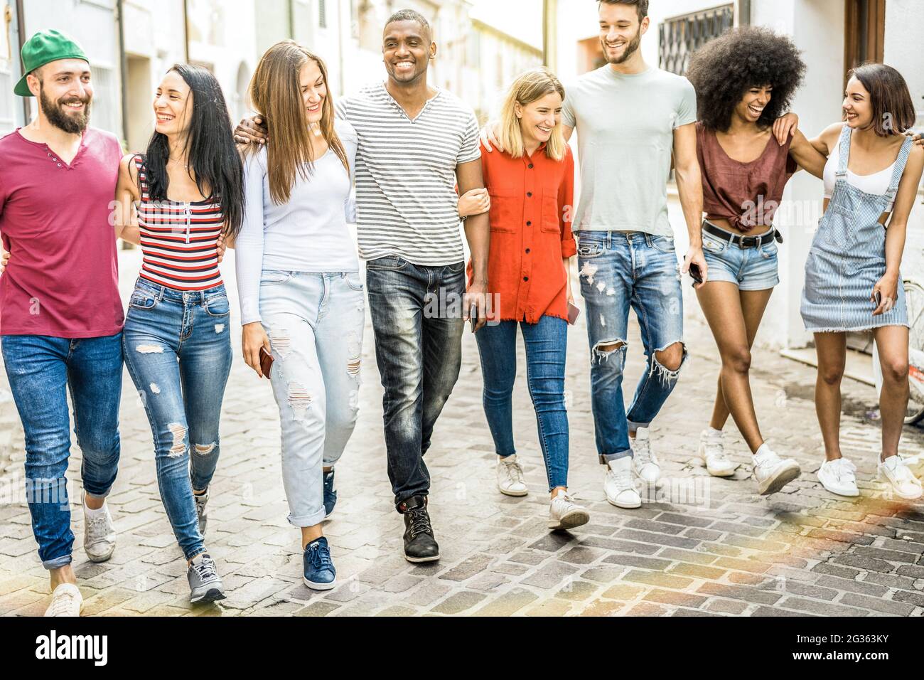 Amici millenari multirazziali che camminano e parlano nel centro della città - ragazzi felici e ragazze che si divertono per le strade della città vecchia - studenti universitari Foto Stock
