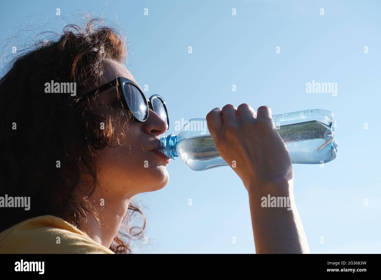 Ragazza con bicchieri beve acqua da una bottiglia in tempo caldo Foto stock  - Alamy
