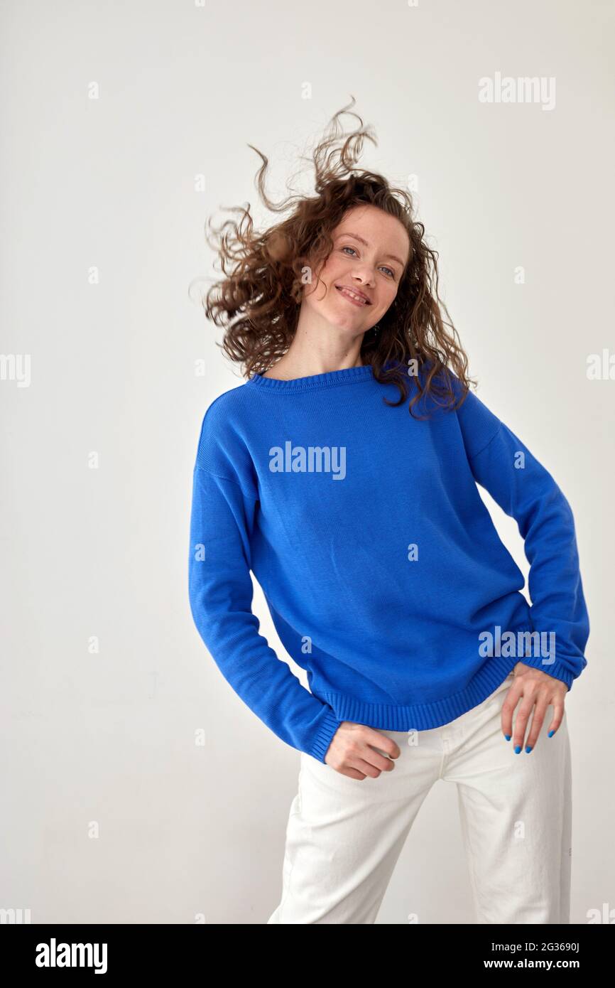 Giovane modello femminile in felpa blu oversize alla moda che guarda la fotocamera su sfondo bianco Foto Stock