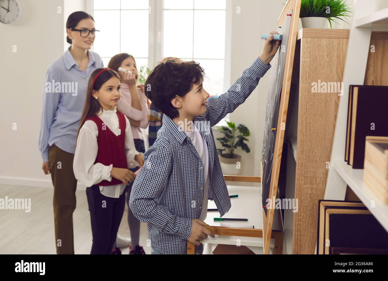 Un bambino intelligente che risponde alla classe durante la lezione scolastica Foto Stock