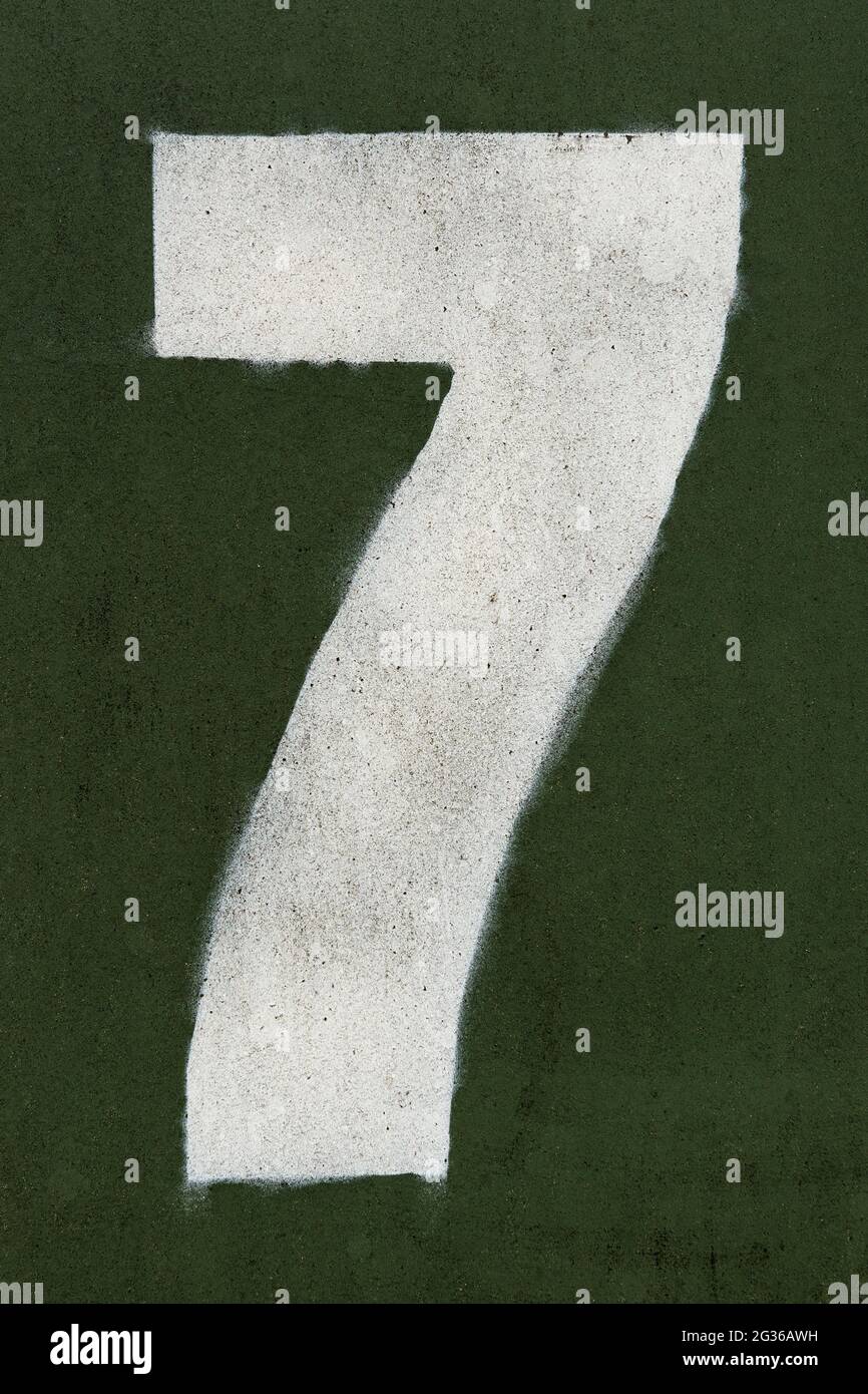 Numero sette spruzzato su una superficie verde scuro Foto Stock