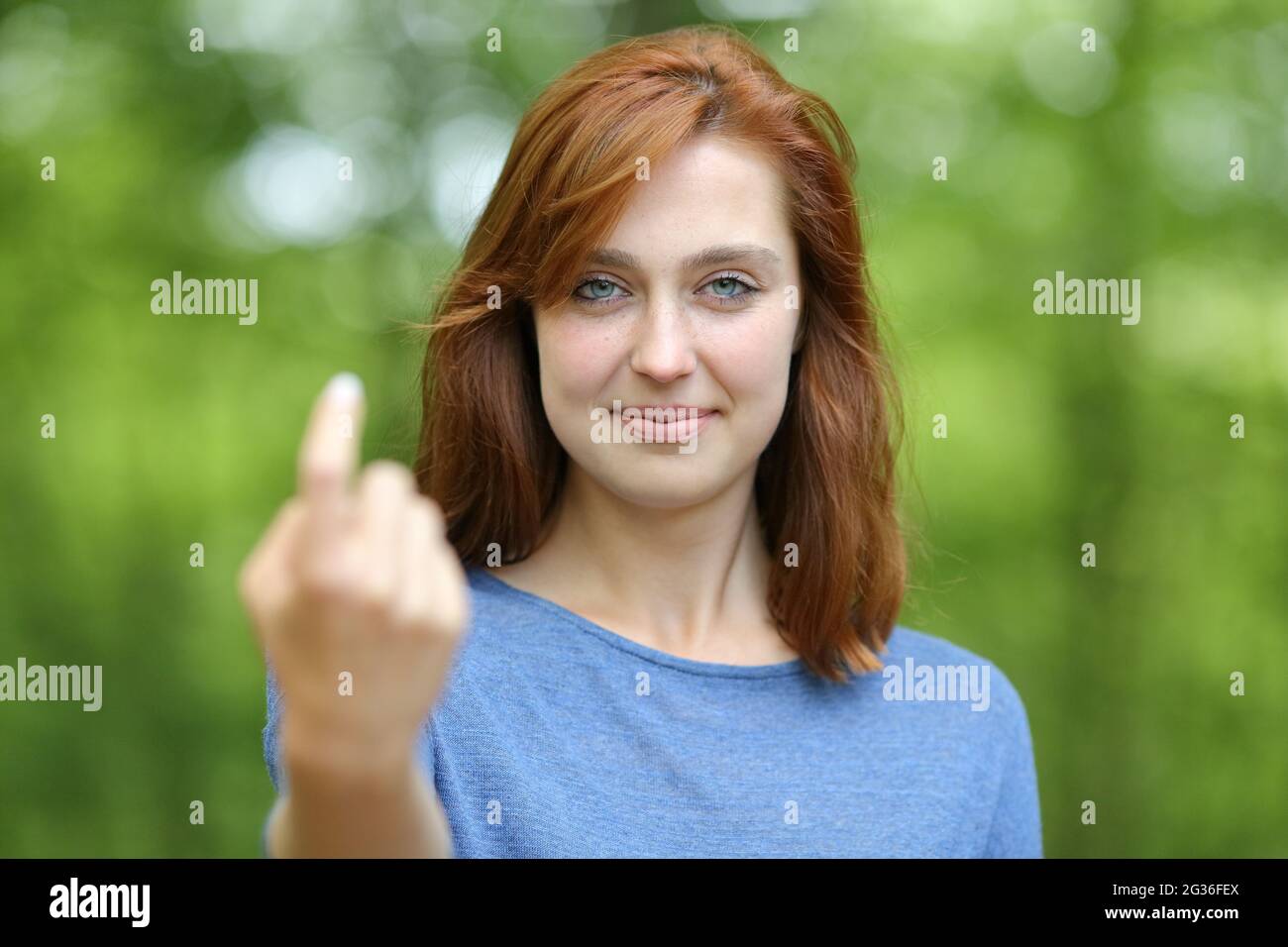 Vista frontale ritratto di una donna rossa che dice venire qui beckoning in una foresta o parco Foto Stock
