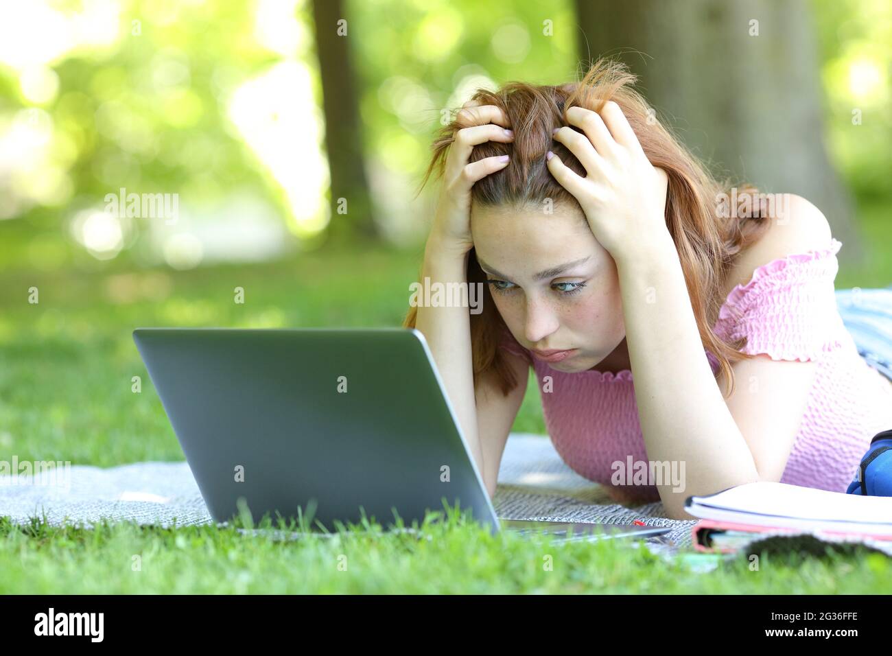 E-learning frustrato per gli studenti che controllano il computer portatile in un parco o in un campus Foto Stock