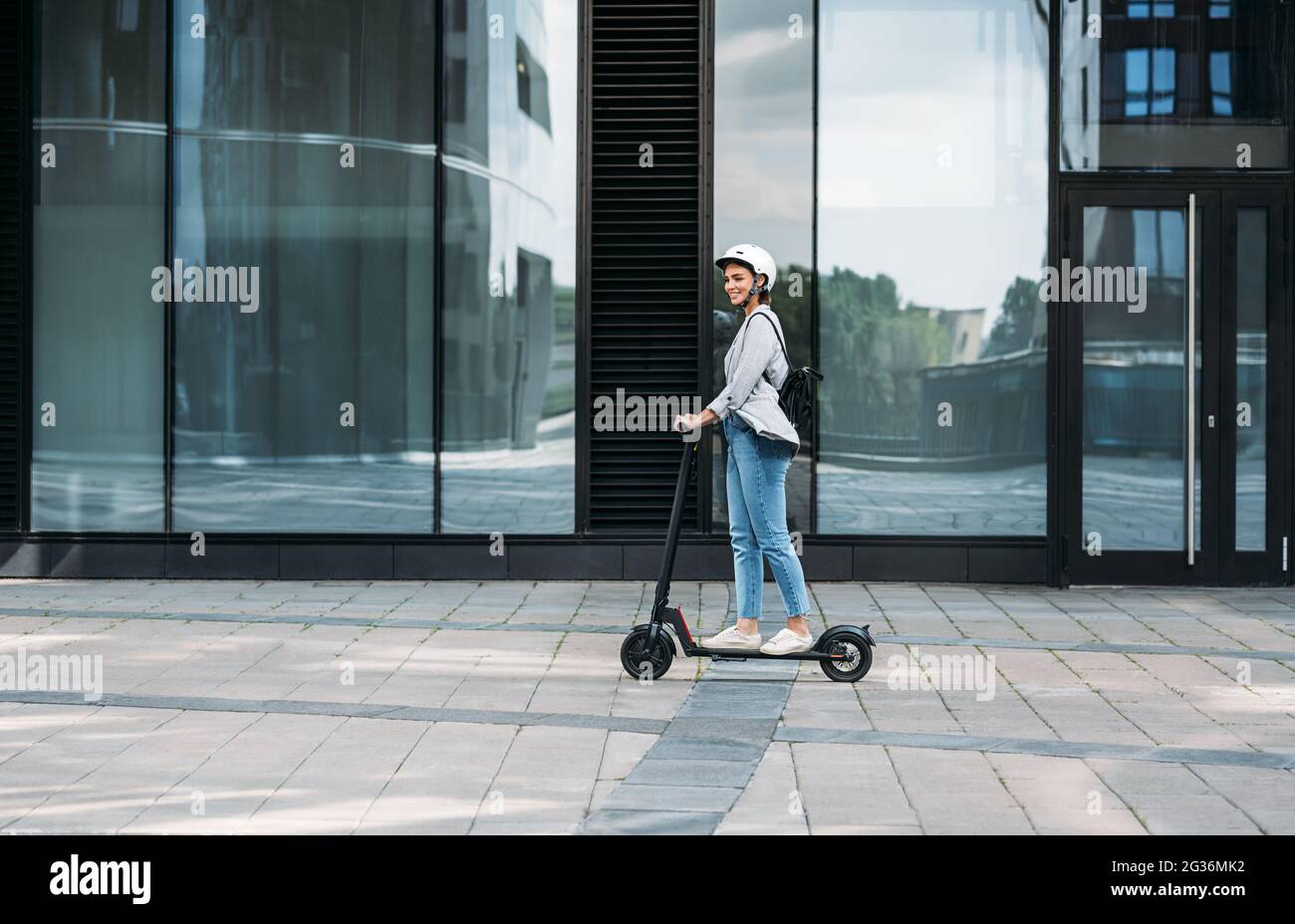 Giovane uomo d'affari che indossa il casco da ciclismo che guida spinga lo scooter sul sentiero Foto Stock