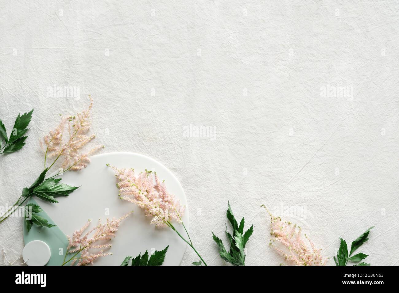 Sfondo naturale estivo con bordo di fiori selvatici. Spazio-copia, posto per il testo. Piatto posato su fondo di lino bianco con rosa pallido selvaggio Foto Stock