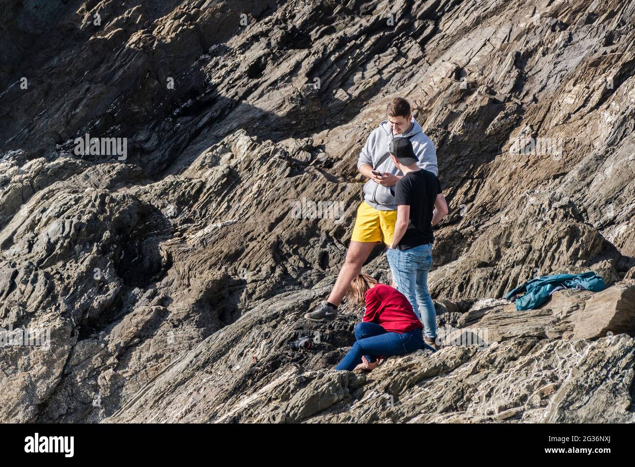 Giovani vacanzieri in piedi su rocce sul promontorio di Towan a Newquay in Cornovaglia. Foto Stock