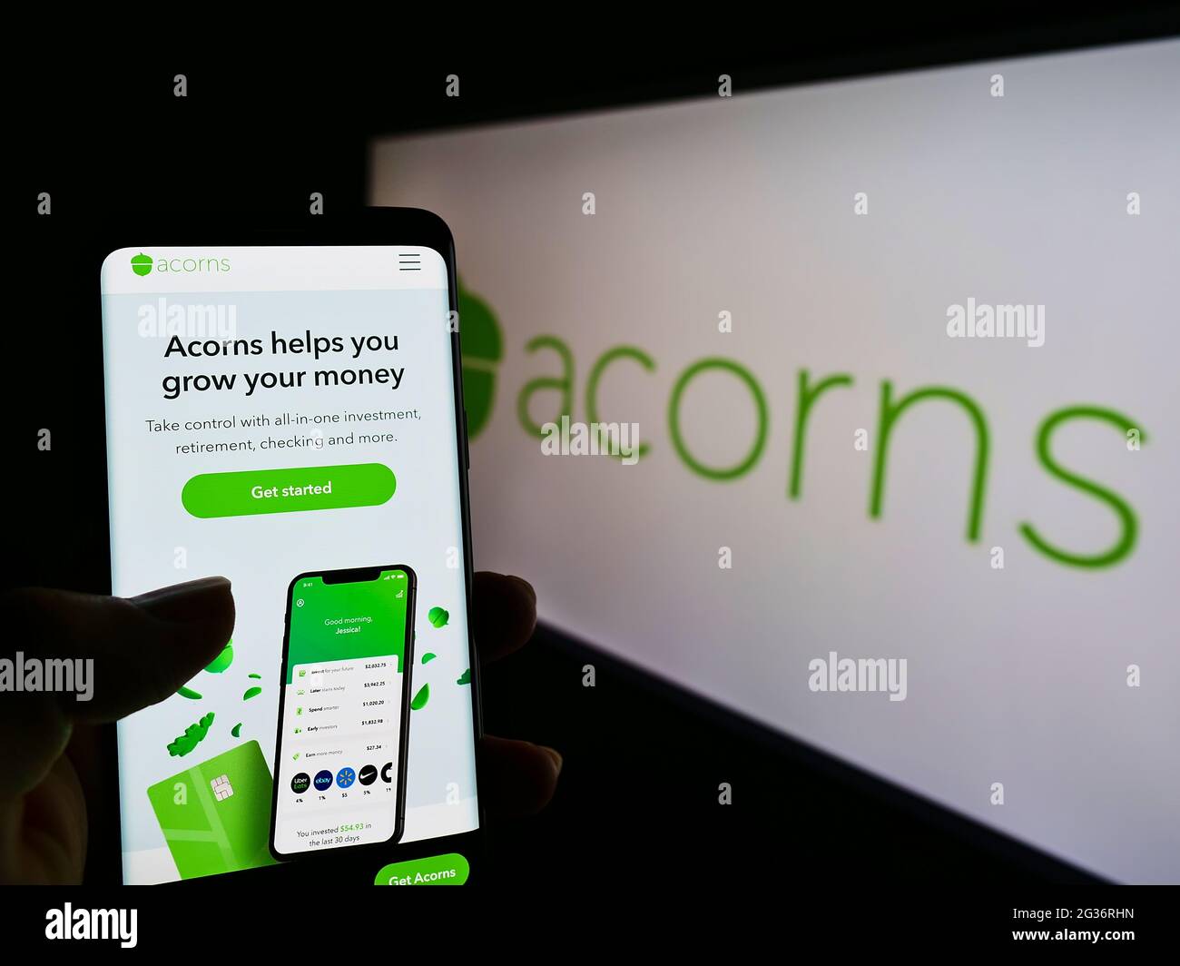 Persona che tiene smartphone con il sito web della società americana di servizi finanziari Acorns Grow Inc sullo schermo di fronte al logo. Mettere a fuoco il centro del display del telefono. Foto Stock