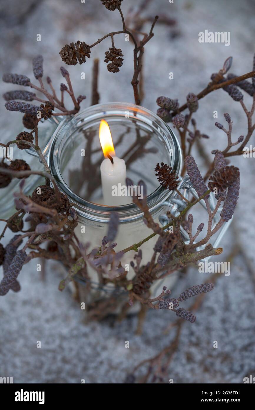lanterna, un vetro è decorato dall'esterno con bastoni, ramoscelli, ramoscelli. Una candela si alza e brucia nel vetro, al riparo dal vento, Foto Stock