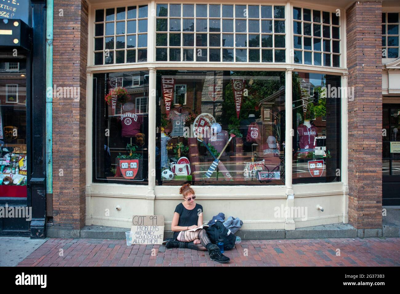 Giovane ragazza senza casa all'Università di Harvard T-shirt libri e negozio di souvenir nel centro della città Massachusetts Avenue, Cambridge, Massachusetts, Stati Uniti Foto Stock