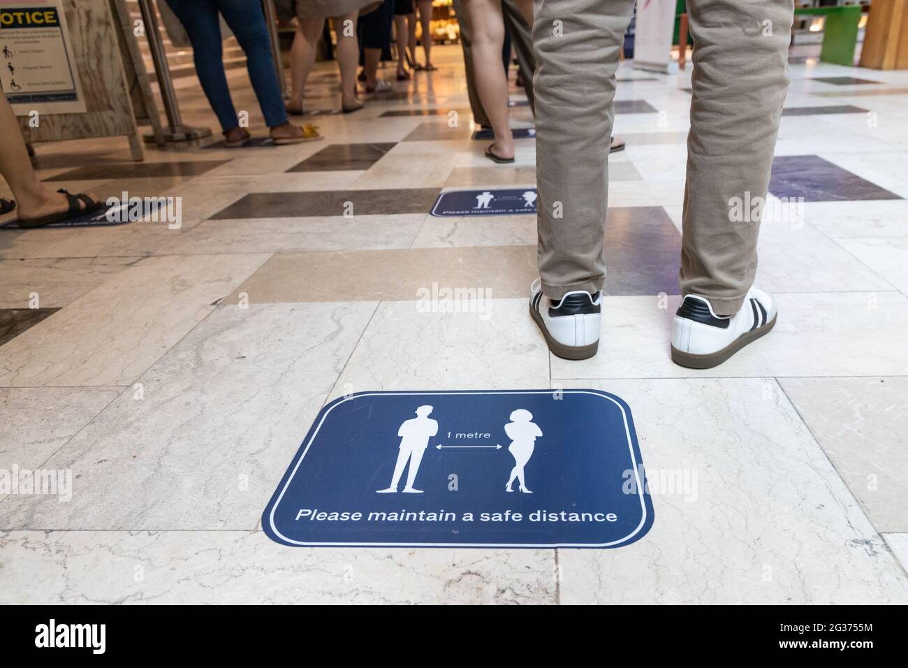 Le persone si accodano in fila per la distanza sociale fisica per entrare nel supermercato per la sicurezza Foto Stock
