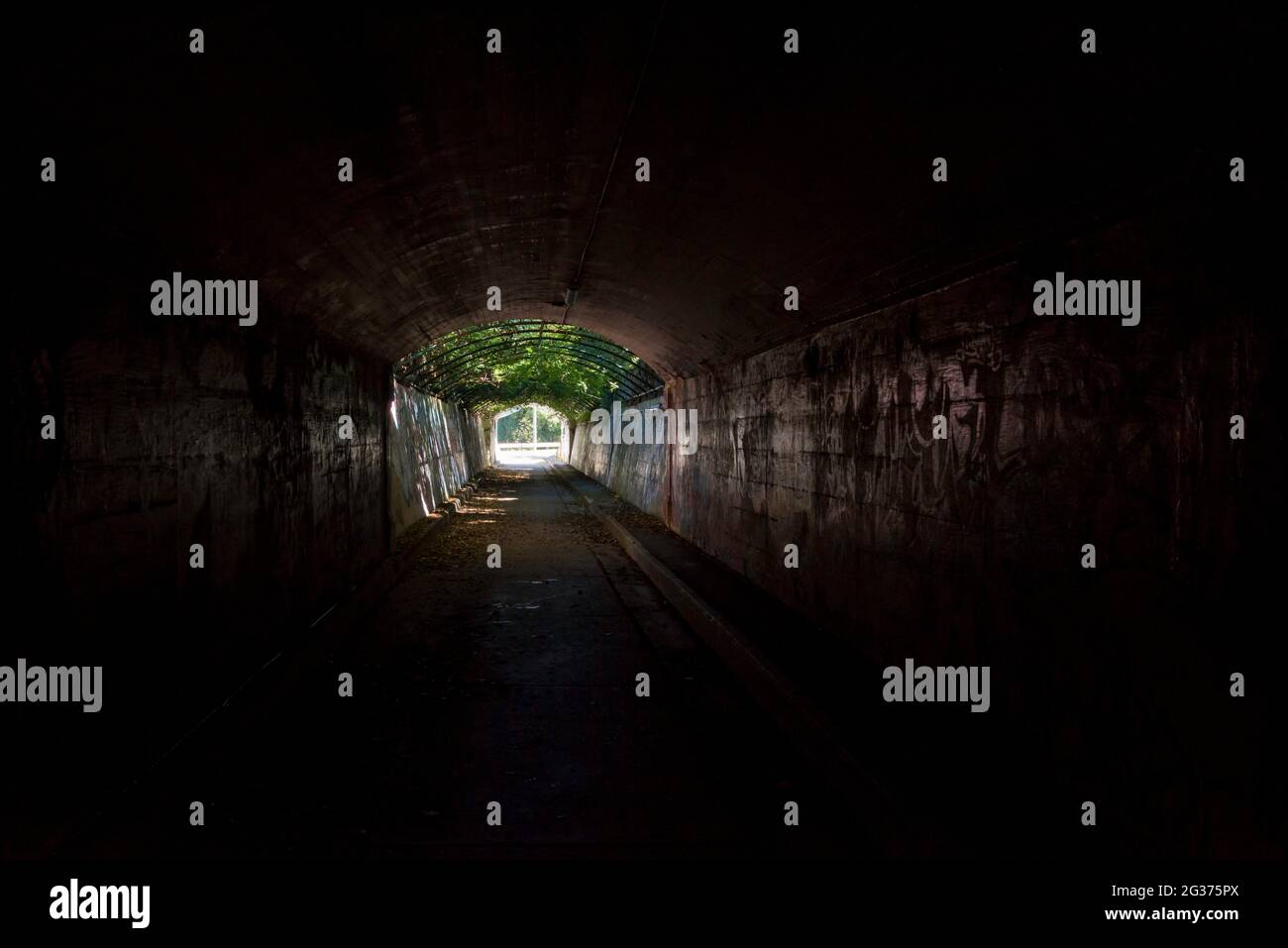 Un tunnel scuro con forte luce solare all'estremità lontana che permette ai pedoni di attraversare sotto Victoria Road vicino al Gladesville Hospital di Sydney, Australia Foto Stock