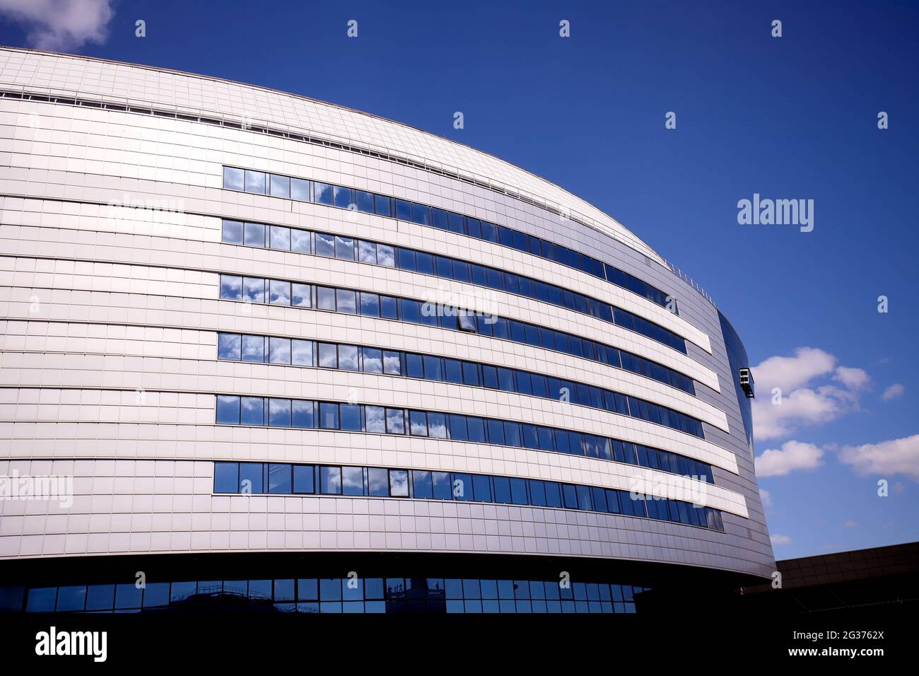 Il nuovo edificio del complesso sportivo contro il cielo blu. Finestre di vetro e il cielo nelle nuvole. Foto Stock