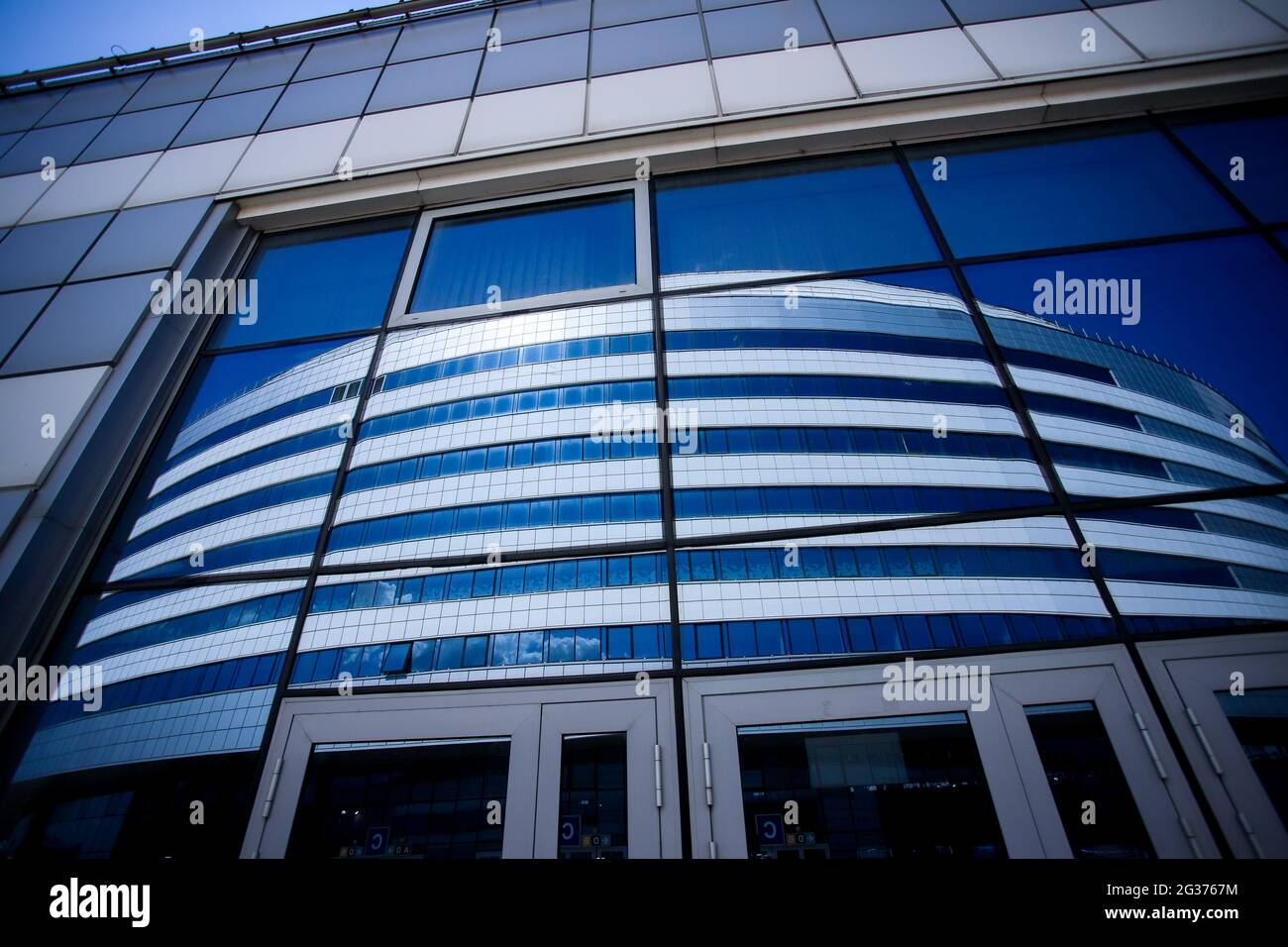 Il nuovo edificio del complesso sportivo contro il cielo blu. Finestre di vetro e il cielo nelle nuvole. Foto Stock