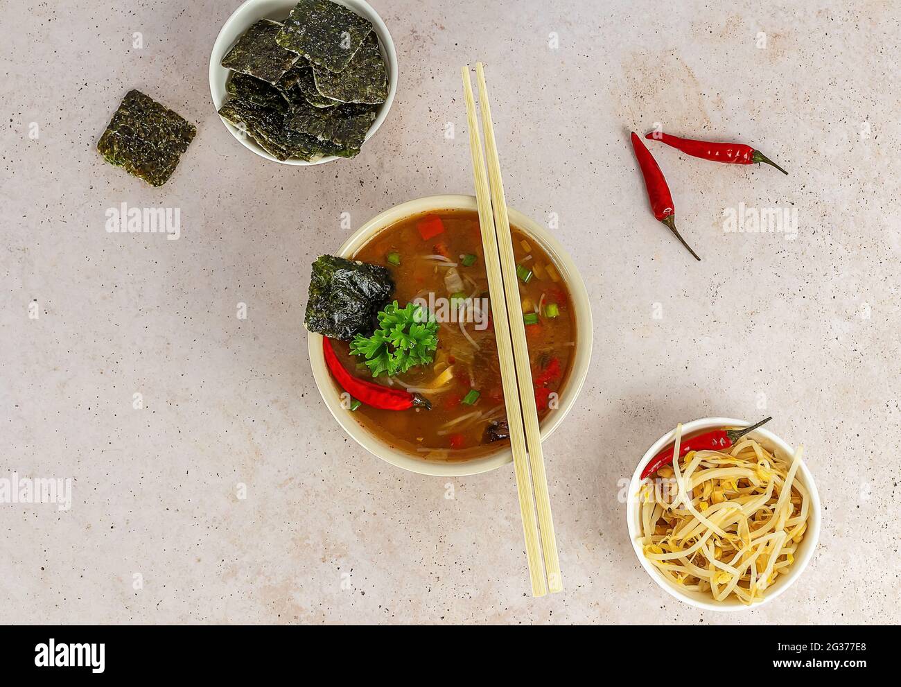 Zuppa asiatica di noodle piccante con alghe e germogli di fagioli. Servita in una ciotola con bastoncini. Vista dall'alto. Foto Stock