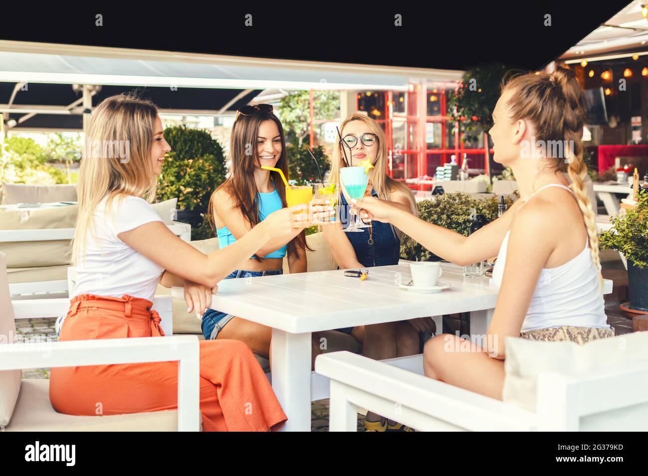Happy giovane ragazza amici tostando cocktail drink al pub ristorante alla moda Foto Stock