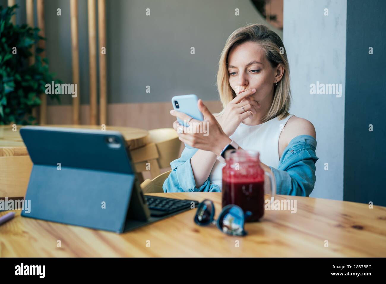 Giovane donna d'affari concentrata che lavora su computer portatile e telefono cellulare Foto Stock