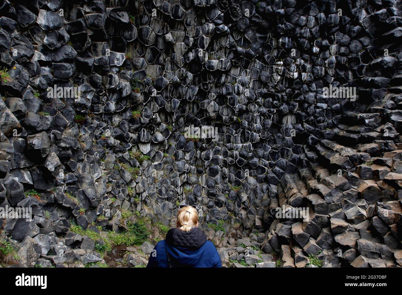 Donna di fronte a colonna basalto, Echo Rock Hljooaklettar, Vestudalur, Islanda del Nord, Islanda Foto Stock