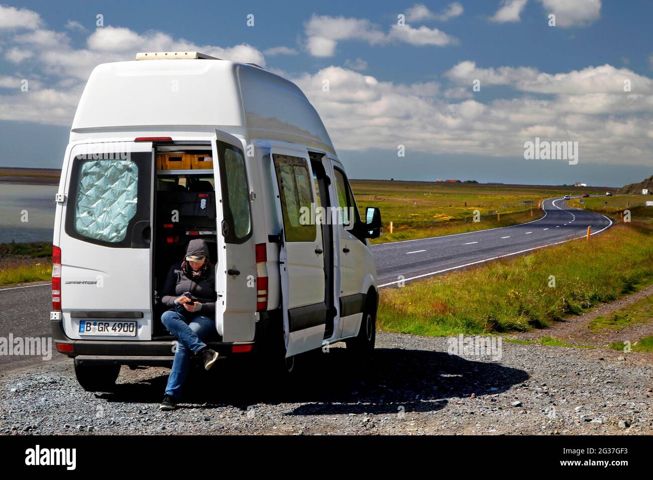 Strada, tangenziale, N 1, Mercedes Sprinter camper, camper, Aprire la porta posteriore, donna seduta nella parte posteriore, Brekkukot, Islanda del Sud, Islanda Foto Stock