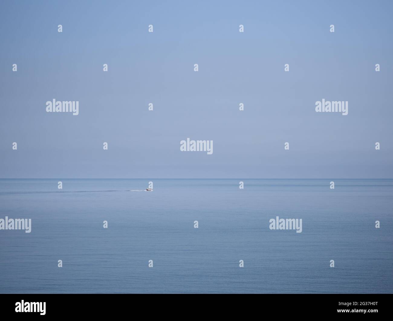 Grande mare, piccola barca. Cielo azzurro e orizzonte. Foto Stock