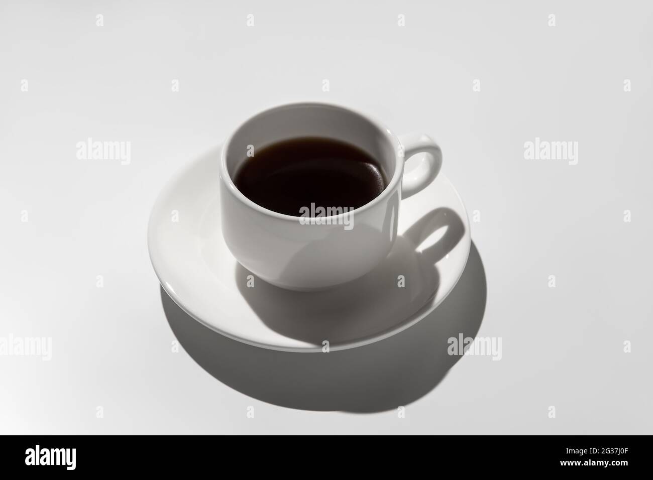 tazza di caffè bianca con espresso. ombre dure su sfondo grigio Foto Stock