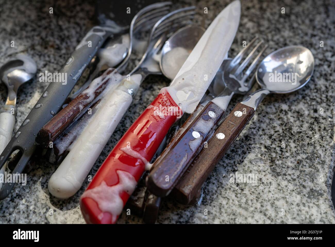 Closeup di coltelli e forcelle ricoperte di sapone su un tavolo da cucina Foto Stock