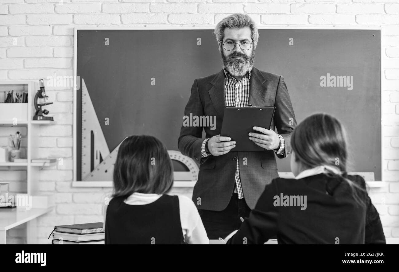 Aula per insegnanti e bambini. Gruppo di discussione di bambini e insegnanti. Dialogo e comunicazione. Vita scolastica quotidiana. Gli amici studiano insieme. Torna a. Foto Stock