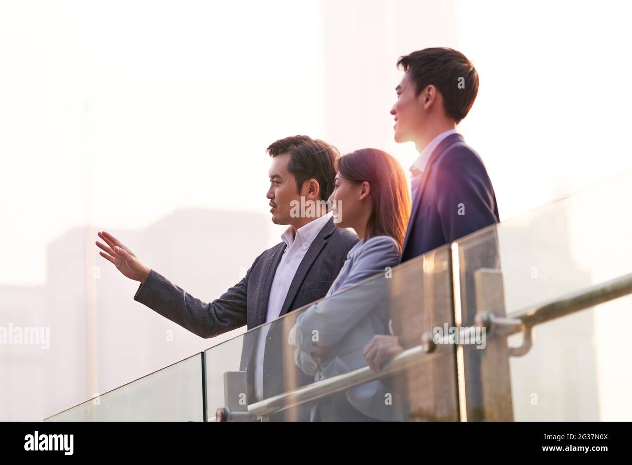 tre uomini d'affari asiatici felici che chiacchierano parlando di affari all'aperto Foto Stock