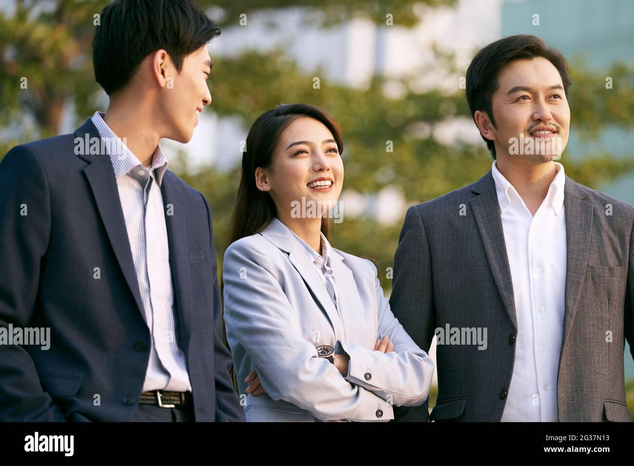un team di tre uomini d'affari asiatici che chiacchierano conversando all'aperto Foto Stock