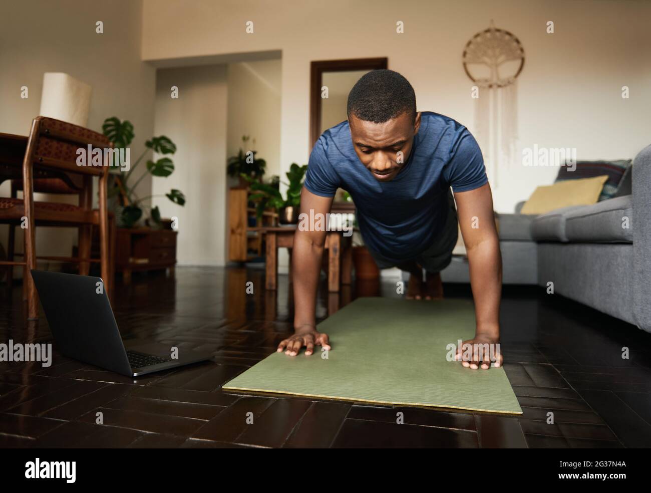 Giovane uomo africano che pianga su un tappeto da ginnastica a casa Foto Stock