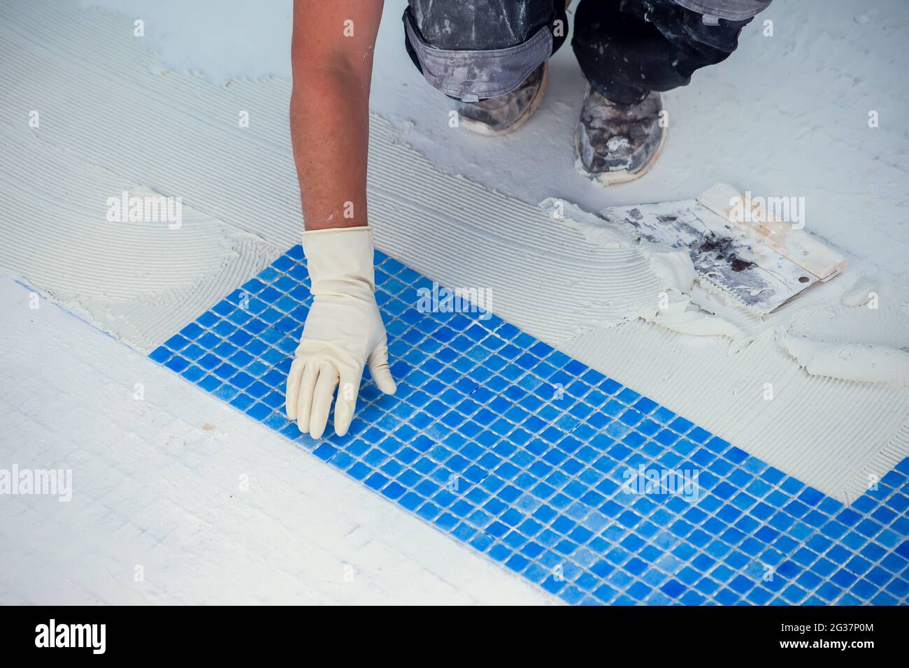Lavoratore posa piastrelle in piscina. Lavori di riparazione della piscina  Foto stock - Alamy