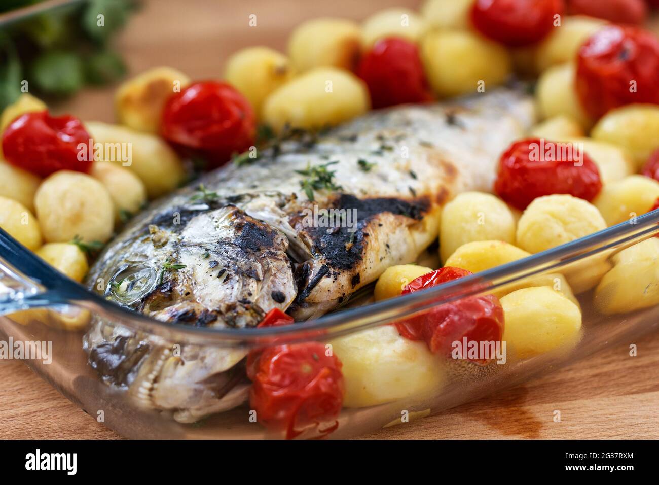 Orata al forno con patate novelle e pomodori ciliegini Foto Stock